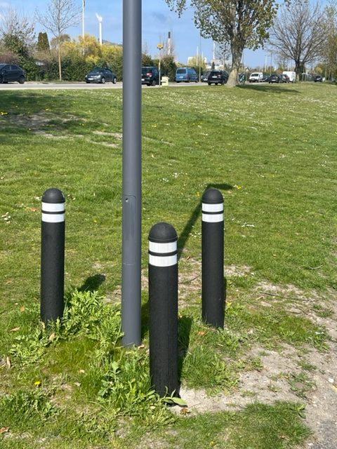 TDJ Nedgravningspullert 140cm i græs, ved lygtepæl, i vejside - fra Trafikgummi.dk. Gummi pullert / steler til nedgravning. Sort med hvide reflekser. Fleksibel.